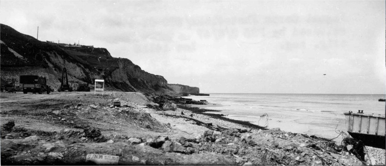Vierville’s seafront in 1944: the cliffs, churned ground, vehicles and the remains of installations on the beach.