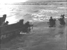 Un LCVP chargé de fantassins Sortie des hommes par l'avant du LCVP, ils se dirigent vers la plage étroite déjà occupée