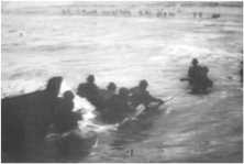 Un LCVP chargé de fantassins Sortie des hommes par l'avant du LCVP, ils se dirigent vers la plage étroite déjà occupée