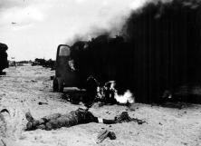 A dead GI in front of a burning GMC truck (details)