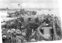 (détails) Un LCT Mk6 (le LCT 30?) au large d'Omaha Beach, passe devant un autre LCT qui transporte des avions d'observation L5 "Piper Cub" chargés avec ailes repliées (dé