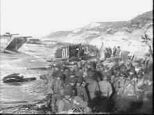 Des GI viennent de débarquer sous les falaises de Colleville. On aperçoit l'aile peinte de rayures blanches d'un avion d'observation de l'artillerie, déchargé dans les gr