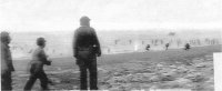 Les 3 GIs en prmeir plan sont abrités par la falaise, mais les soldats sur la plage sont sous le feu et certains tombent