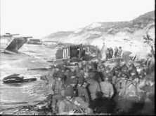 Attempts were made to unload an artillery observation Piper Cub aircraft in the middle of the large pebbles under the cliff of Colleville
