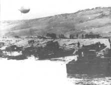 Marée haute le 7 juin, des débris partout (détails) Au milieu un char détruit devant le talus de galets (détails) Un Sherman standard (le Ceaseless, du 743ème Tk Bn) détr