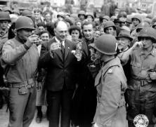 (détails) A la fête du 4 juillet 1944- Une jeune fille, Marguerite Lemoussu, sert à boire à des soldats américains et anglais ou canadiens sur la place de Trévières. La p