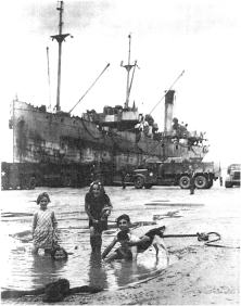 (details) A caboter discharges directly into the low tide pre-port, while children play. This happened when the port of Oimaha Beach was out