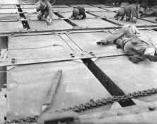 (détails) Un causeway en construction Un LCT approche d'un causeway, mais des chasseurs-bombardiers Allemands inquiètent les GI qui s'aplatissent à terre Marins travailla